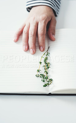 Buy stock photo Cropped shot of an unrecognizable woman's hand touching an open notebook that has a plant sample placed on it