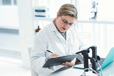 Buy stock photo Cropped shot of an attractive young female scientist filling a document while using a laptop in a laboratory