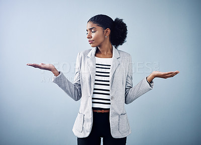 Buy stock photo Female thinking about a business option or choice for a decision between offers. Confused, anxious female shrugging, doing balance hand gesture with a grey copyspace background.