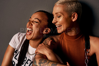 Buy stock photo Cropped shot of two attractive young girlfriends laughing together while sitting against a dark background