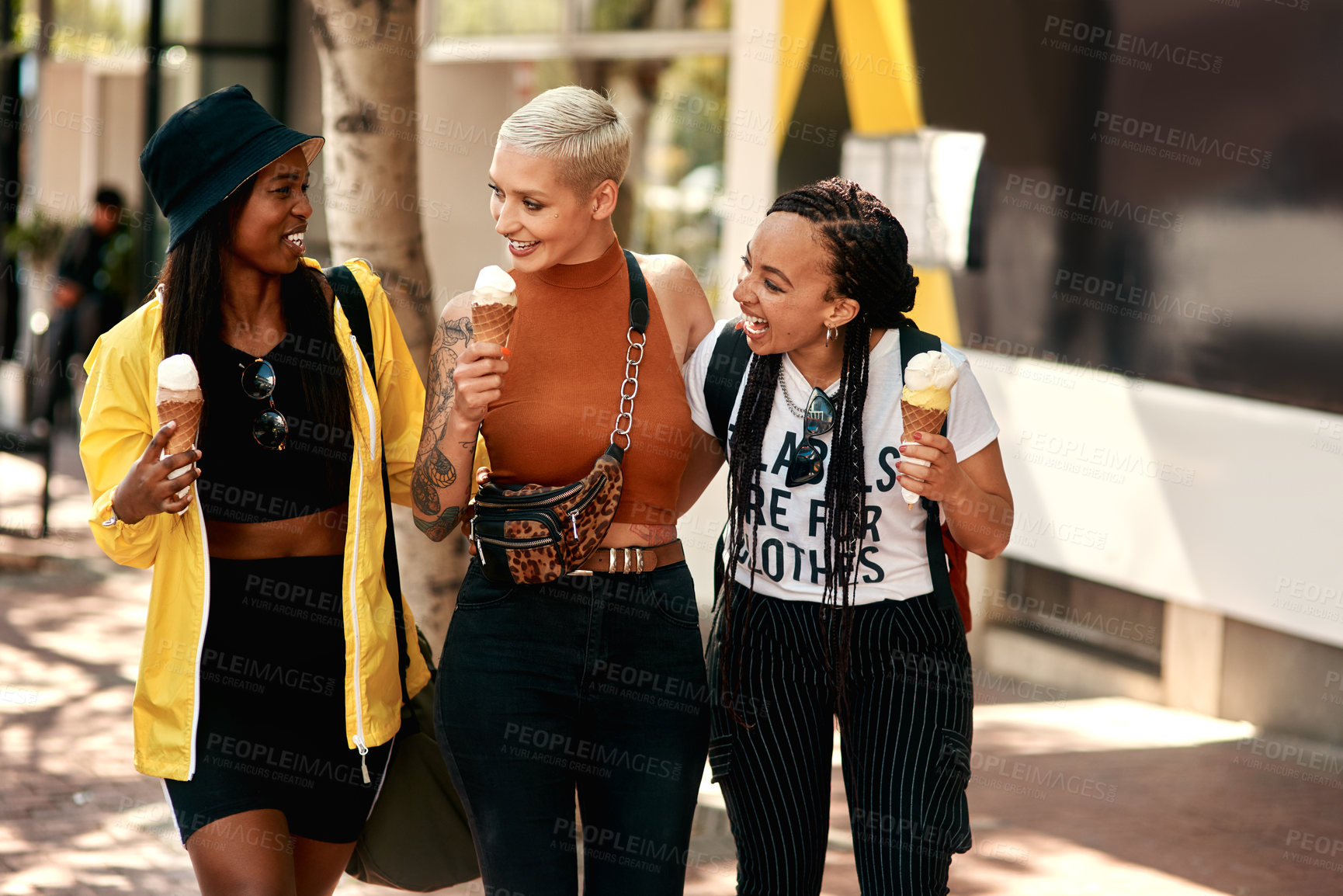 Buy stock photo Shot of three friends enjoying ice cream cones while out in the city