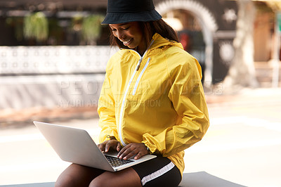 Buy stock photo Shot of an attractive young woman using a laptop while relaxing outdoors in the city