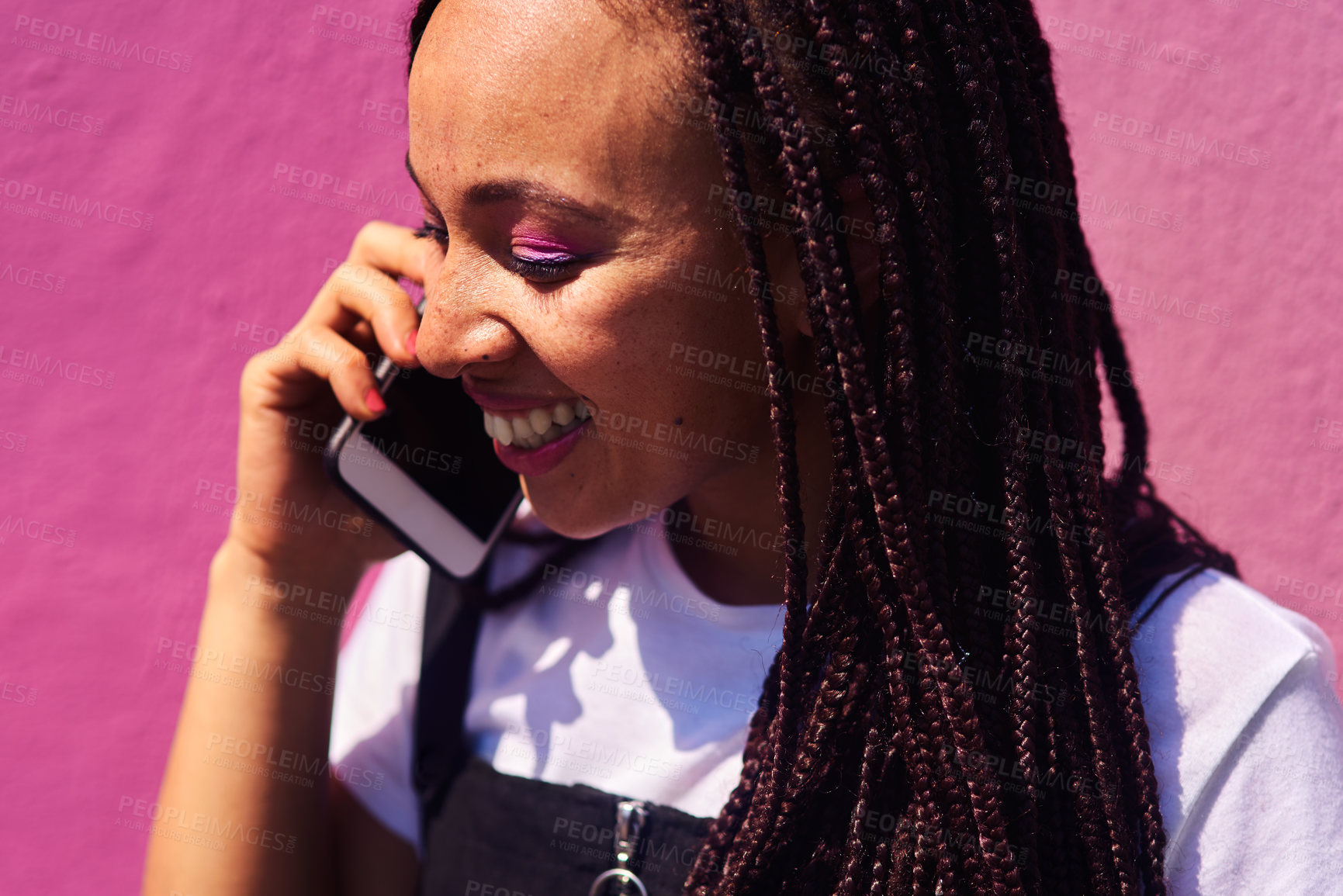 Buy stock photo Cropped shot of an attractive young woman standing against a pink wall alone and talking on her cellphone