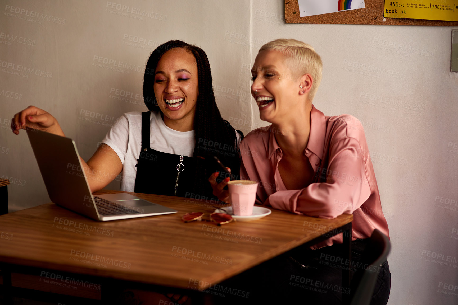 Buy stock photo Shot of two attractive young women using a laptop while relaxing together inside a cafe