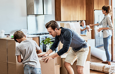 Buy stock photo Cropped shot of a focused young family of four working together to unpack boxes in their new home on moving day