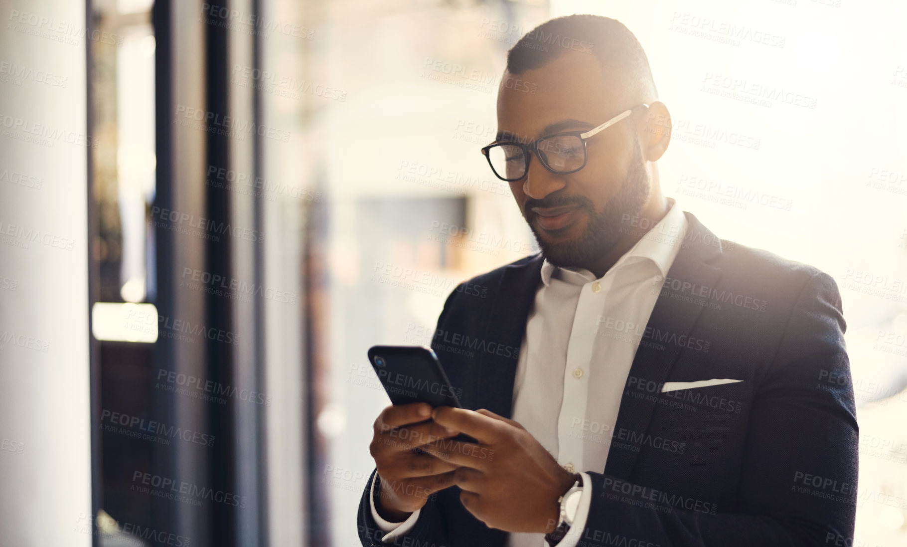 Buy stock photo Shot of a young businessman using a cellphone in an office