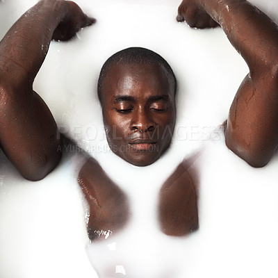 Buy stock photo Shot of a muscular young man having a milky bath at home