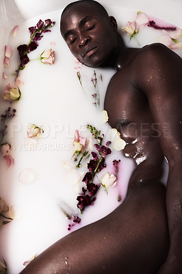 Buy stock photo Shot of a muscular young man having a milky bath filled with flowers at home