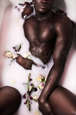 Buy stock photo Cropped shot of a muscular young man having a milky bath filled with flowers at home