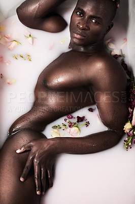 Buy stock photo Shot of a muscular young man having a milky bath filled with flowers at home