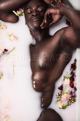 Buy stock photo Cropped shot of a muscular young man having a milky bath filled with flowers at home