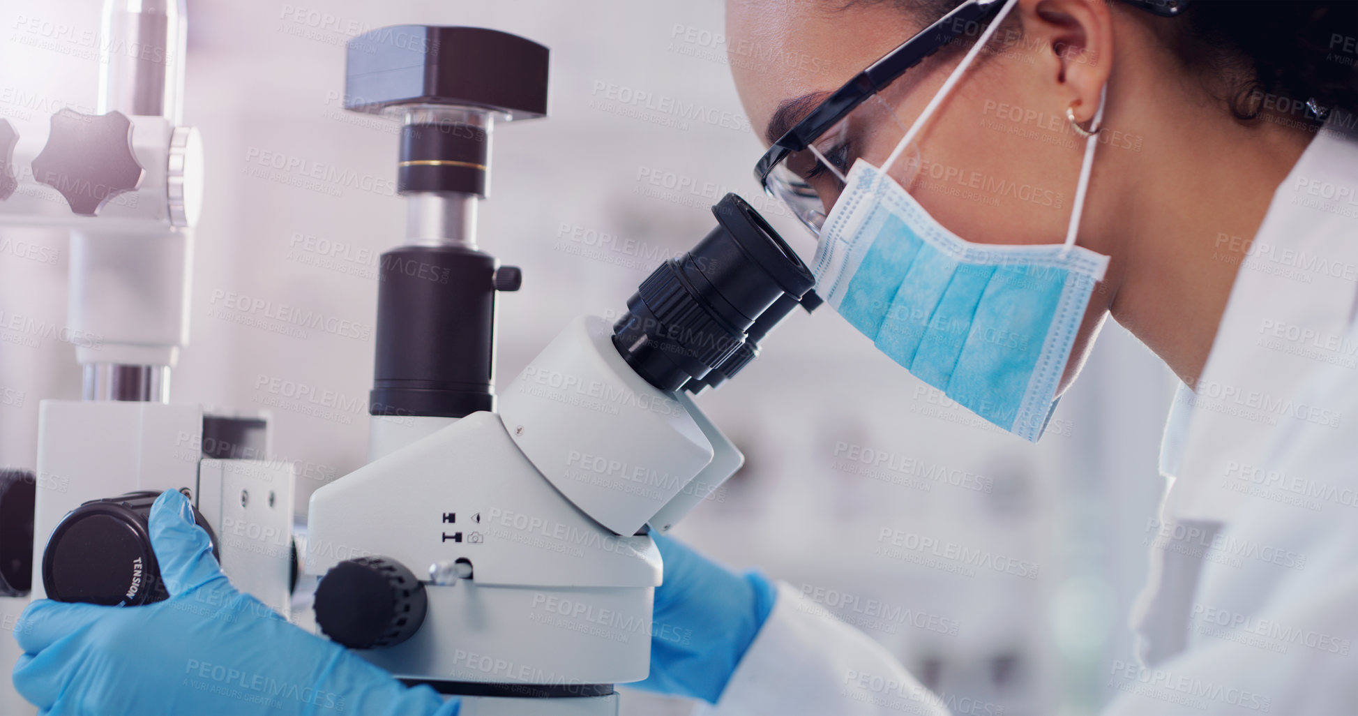 Buy stock photo Shot of a young scientist using a microscope in a lab