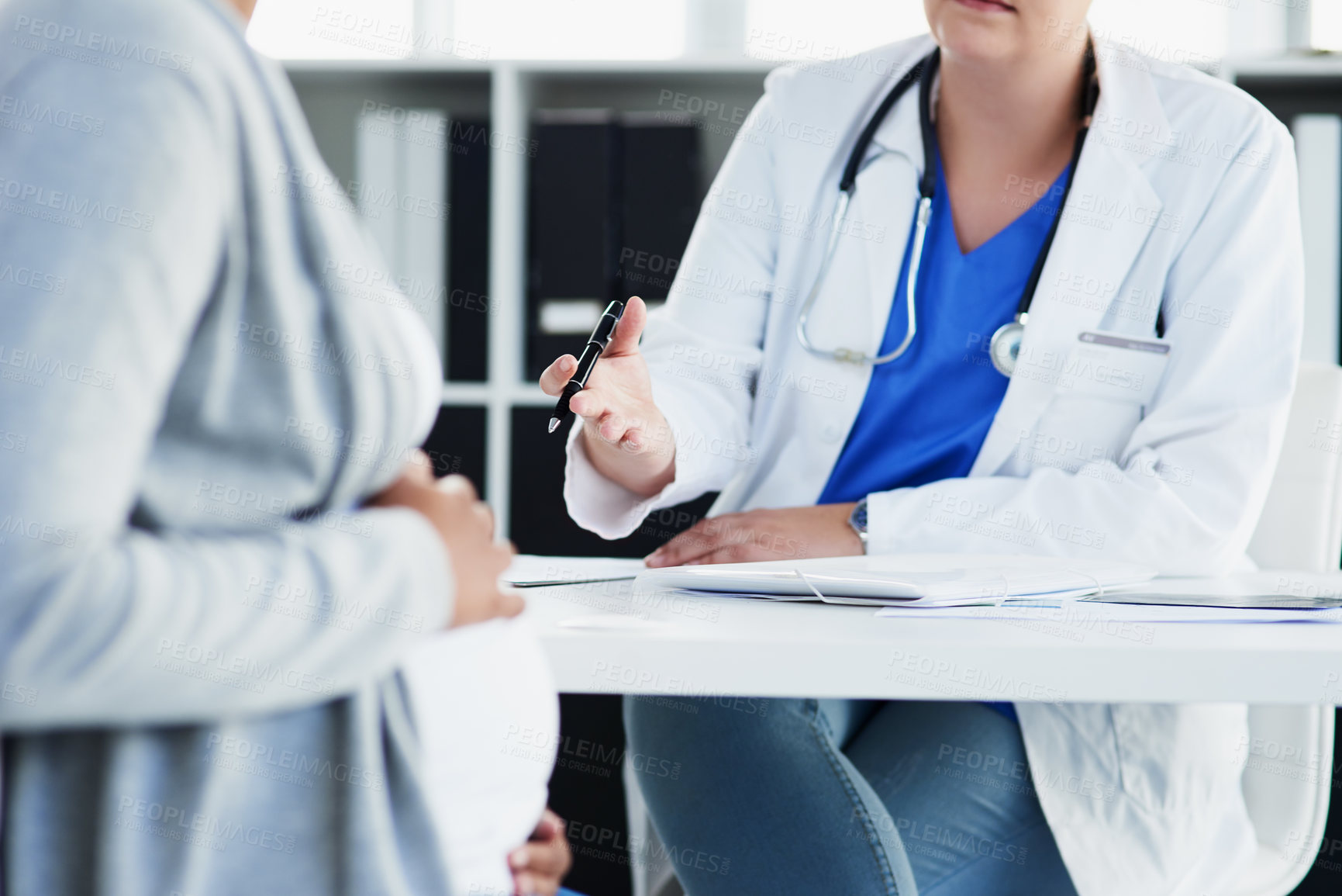 Buy stock photo Cropped shot of an unrecognizable female doctor consulting with a pregnant patient at a hospital during the day