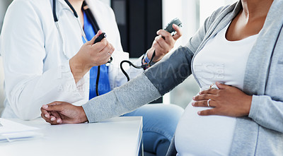 Buy stock photo Cropped shot of an unrecognizable female doctor checking the blood pressure of a pregnant patient at a hospital during the day