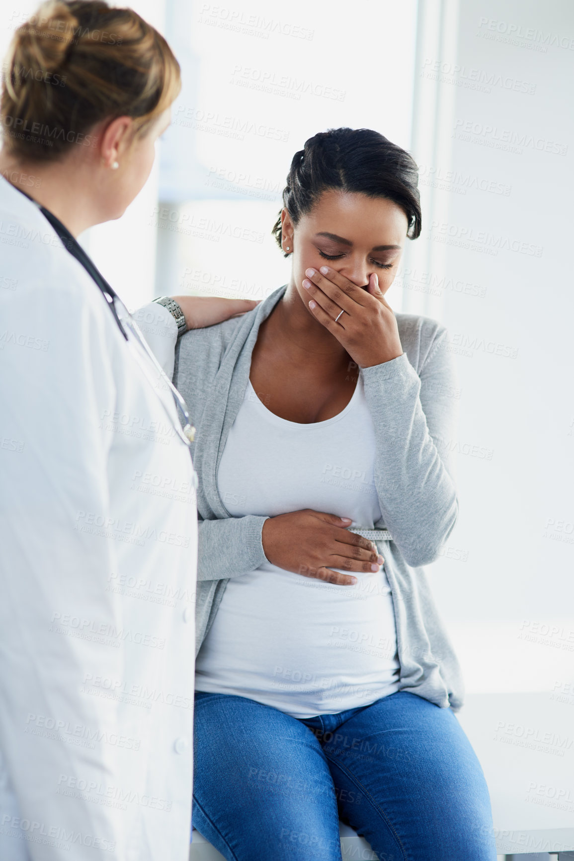 Buy stock photo Cropped shot of a young female doctor trying to comfort a distressed pregnant patient at a hospital during the day