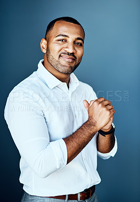Buy stock photo Cropped portrait of a handsome young businessman standing alone against a studio background with his hands clasped together