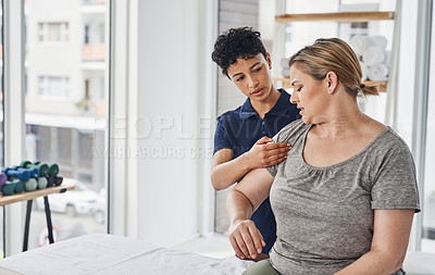 Buy stock photo Shot of a young physiotherapist treating a mature woman inside her office at a clinic