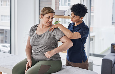 Buy stock photo Shot of a young physiotherapist treating a mature woman inside her office at a clinic