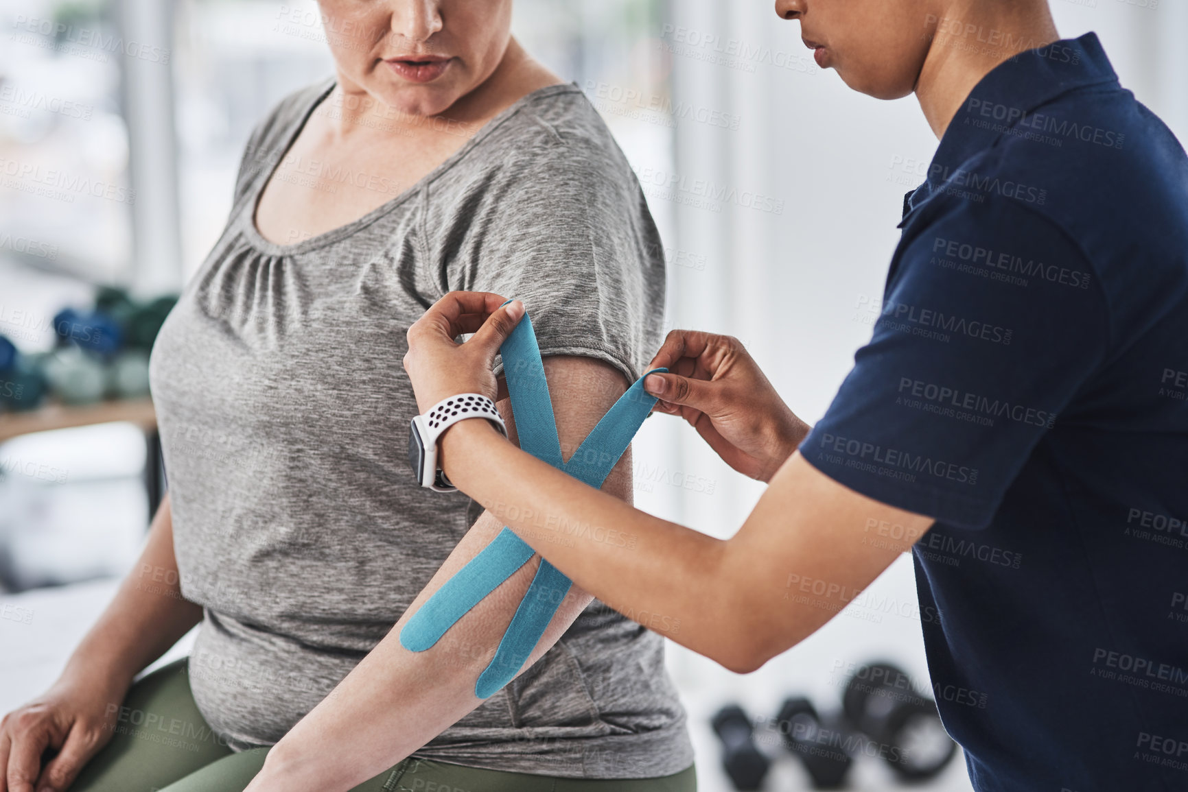 Buy stock photo Shot of an unrecognizable physiotherapist putting kinesiology tape on a patient's arm at a clinic