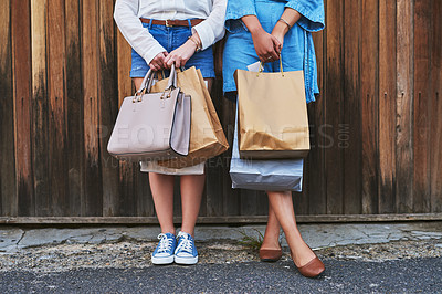 Buy stock photo Cropped shot of two unrecognizable girlfriends standing together while holding shopping bags against a wooden background