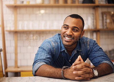 Buy stock photo Cropped shot of a handsome young businessman leaning on the counter in his cafe with his hands clasped