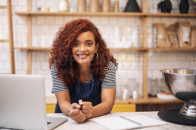 Buy stock photo Cropped shot of an attractive young businesswoman leaning on a counter in her cafe before working on her laptop
