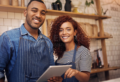 Buy stock photo Cropped shot of two young business owners standing together in their cafe and using a tablet