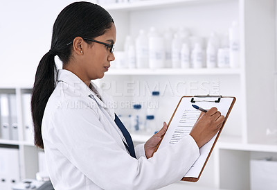 Buy stock photo Cropped shot of an attractive young female scientist working on a clipboard in her laboratory