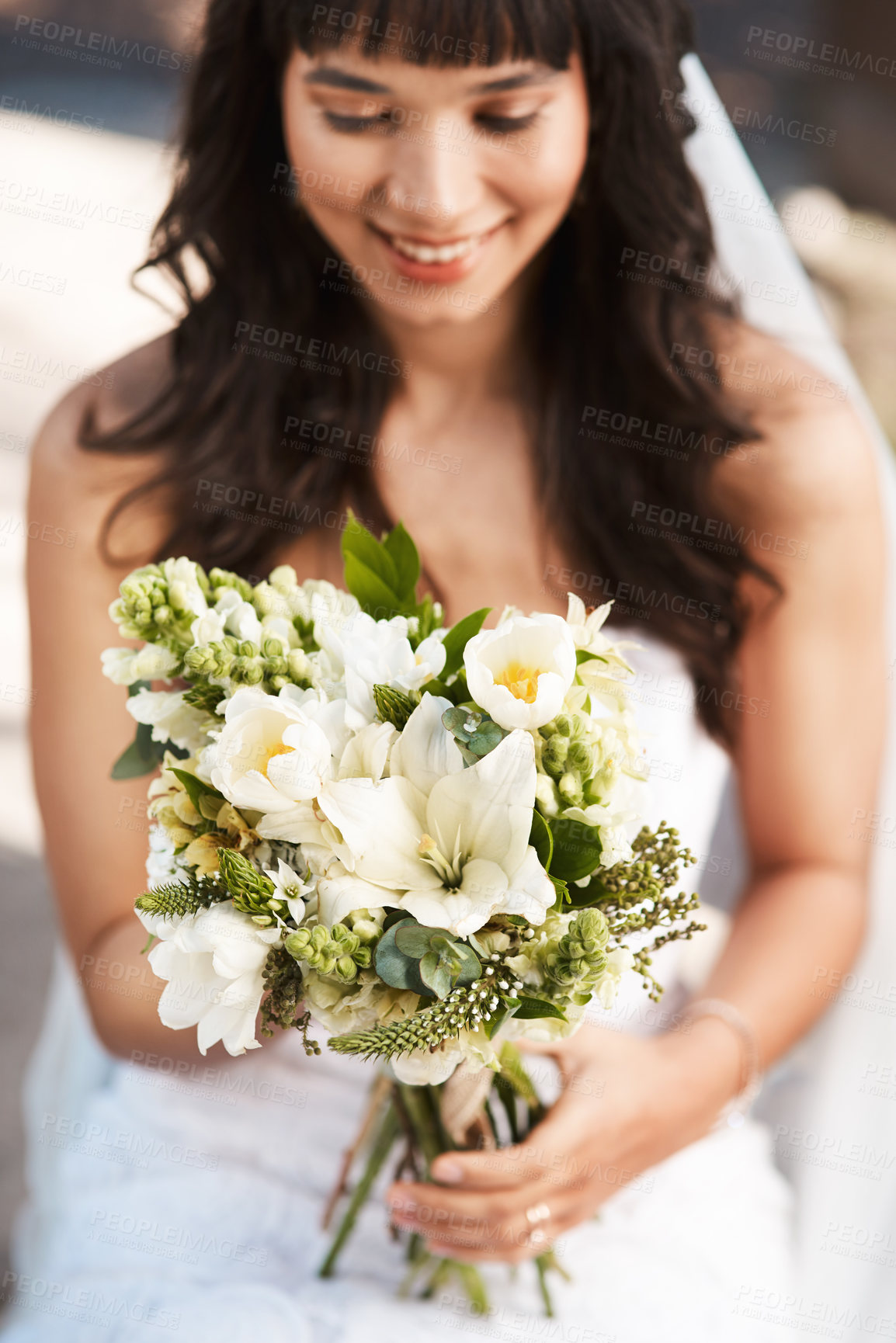 Buy stock photo Cropped shot of a beautiful young bride holding a bouquet of flowers while sitting outdoors on her wedding day