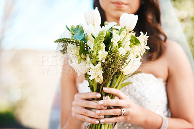 Buy stock photo Cropped shot of an unrecognizable bride holding a bouquet of flowers while standing outdoors on her wedding day