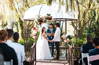 Buy stock photo Cropped shot of a handsome young male marriage officiant joining a young couple in marriage outdoors