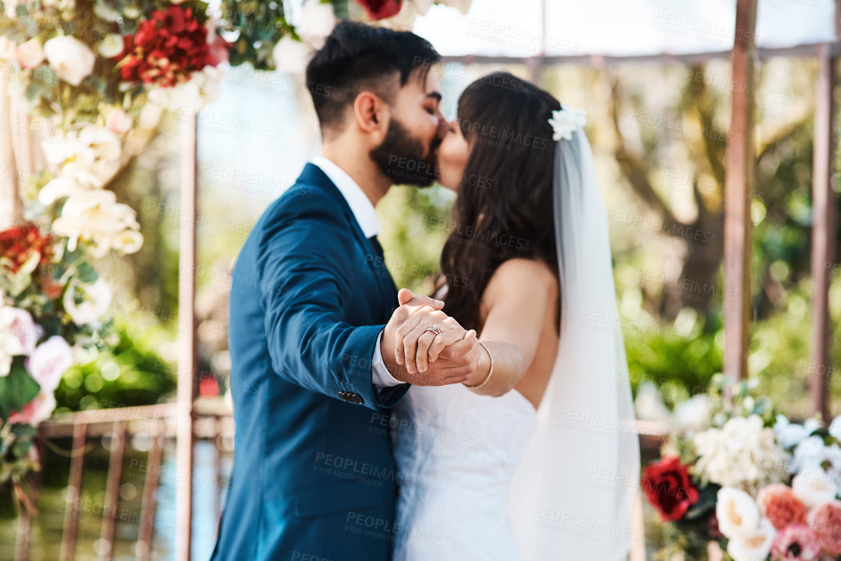 Buy stock photo Cropped shot of an unrecognizable newlywed couple kissing while holding hands on their wedding day