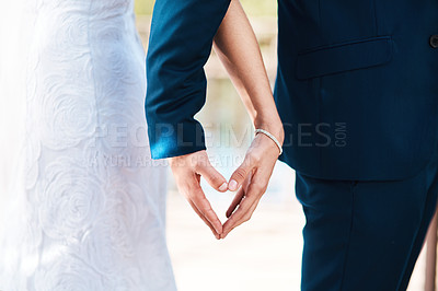 Buy stock photo Cropped shot of an unrecognizable newlywed couple making a heart shape with their hands while standing outdoors on their wedding day