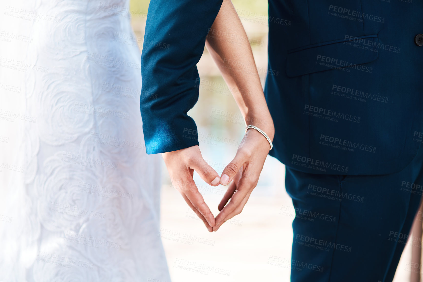 Buy stock photo Cropped shot of an unrecognizable newlywed couple making a heart shape with their hands while standing outdoors on their wedding day