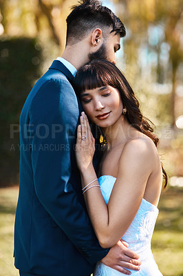 Buy stock photo Cropped shot of an affectionate young bride leaning on her groom's chest while standing outdoors on their wedding day