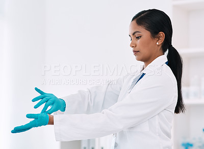 Buy stock photo Cropped shot of an attractive young female scientist taking off her gloves while working in a laboratory