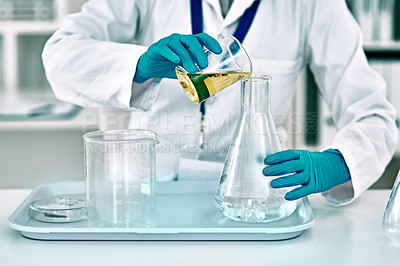 Buy stock photo Cropped shot of an unrecognizable female scientist transferring a gold liquid from a beaker to a conical flask while working in a laboratory