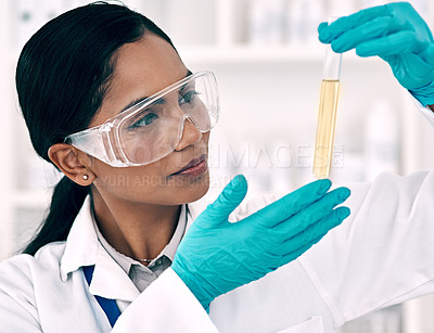Buy stock photo Cropped shot of an attractive young female scientist inspecting a test tube containing a gold liquid while working in a laboratory