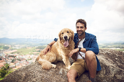 Buy stock photo Cropped shot of a handsome young man sitting on a rock with his golden retriever after a day out hiking