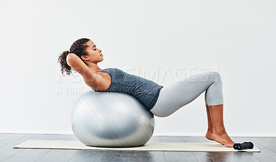 Buy stock photo Shot of a young woman exercising using a fitness ball