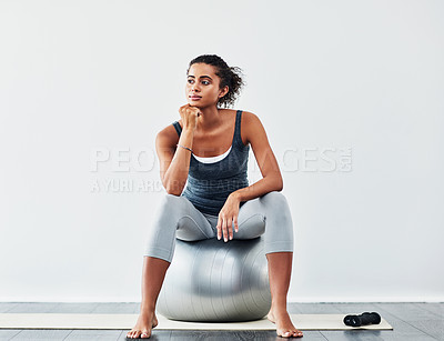 Buy stock photo Shot of a sporty young woman sitting on a exercise ball