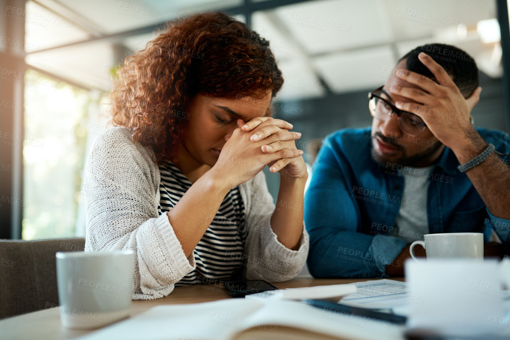 Buy stock photo Shot of a young couple looking stressed out while working on their budget at home