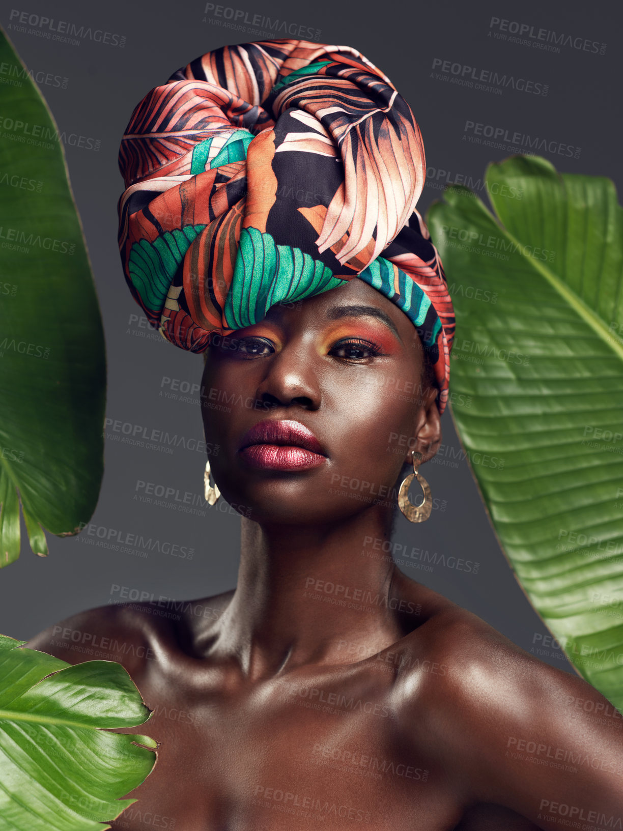 Buy stock photo Studio shot of a beautiful young woman wearing a traditional African head wrap against a leafy background