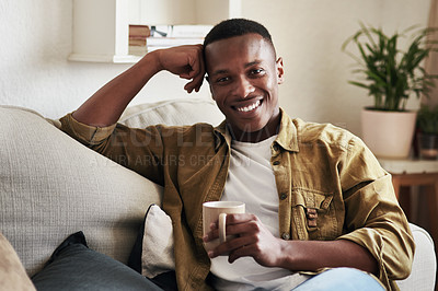 Buy stock photo Cropped portrait of a handsome young man smiling while having coffee on his couch at home
