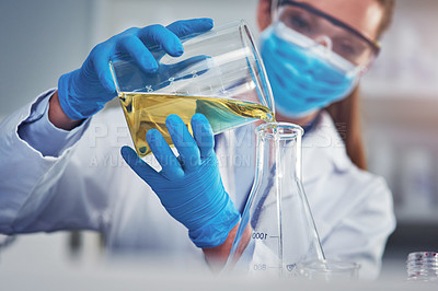 Buy stock photo Cropped shot of an unrecognizable female scientists wearing a protective face mask while mixing chemicals together inside of a laboratory