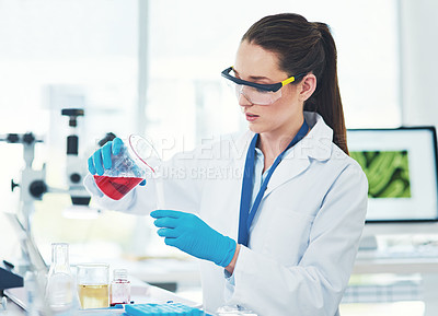 Buy stock photo Cropped shot of a focused young female scientist mixing chemicals together inside of a laboratory during the day
