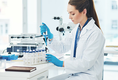 Buy stock photo Cropped shot of a focused young female scientist pouring a test sample into a vile inside of a laboratory