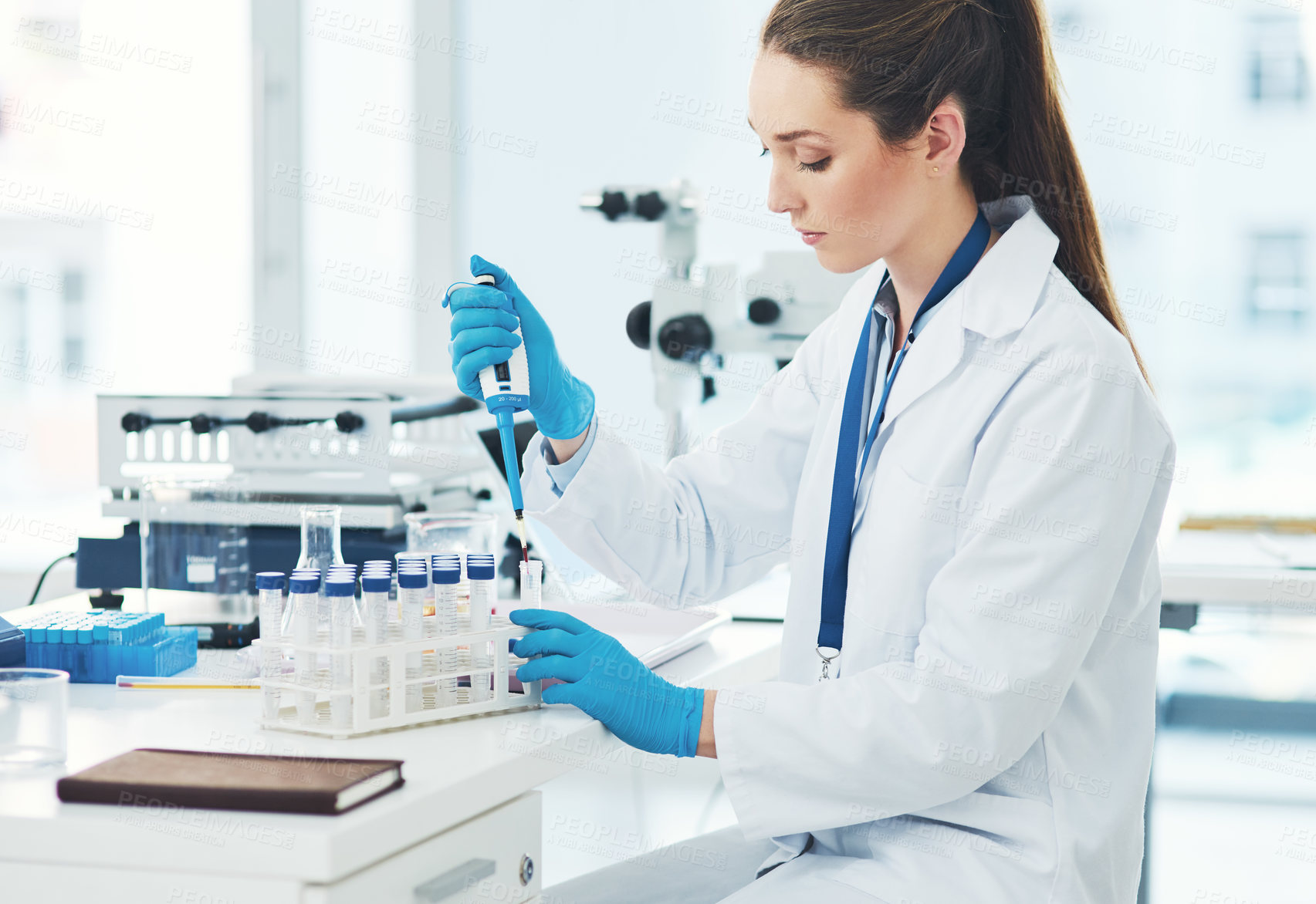 Buy stock photo Cropped shot of a focused young female scientist pouring a test sample into a vile inside of a laboratory