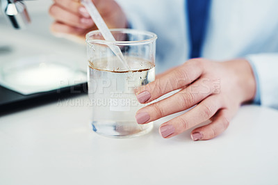 Buy stock photo Closeup of an unrecognizable scientist mixing chemicals together at their desk inside of a laboratory