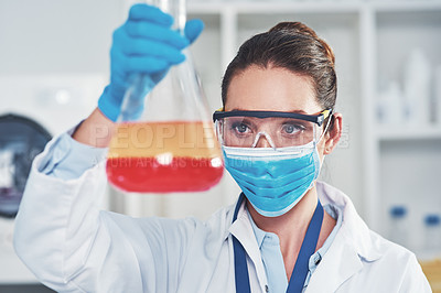 Buy stock photo Cropped shot of an unrecognizable young female scientist wearing protective face gear while holding up a test tube inside of a laboratory